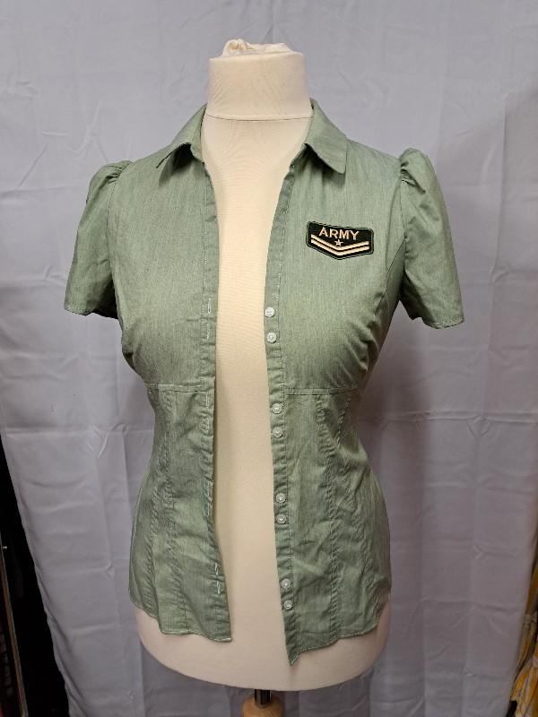Green blouse (shown on a dummy unbuttoned) with short sleeves, collar, and army badge on the left breast