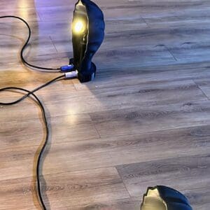 3x Black scallop shell footlights shown on a wooden dance floor with powercon cables between them